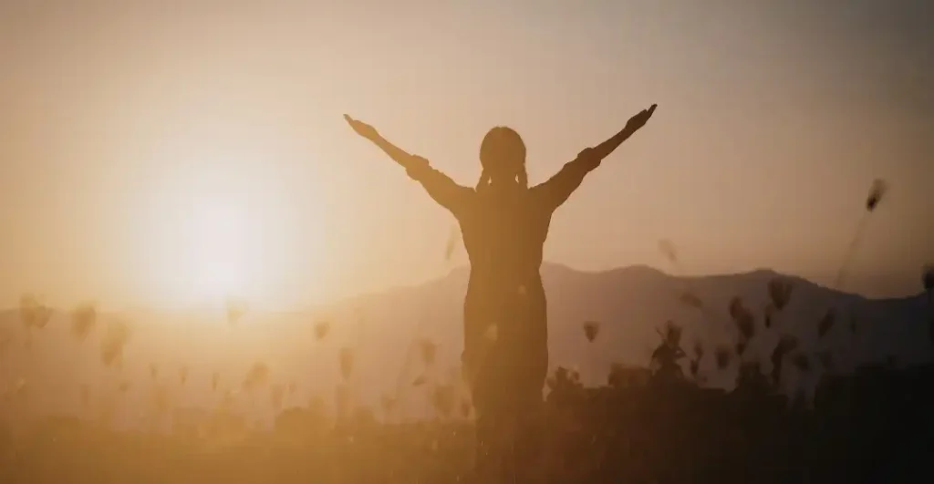 A person standing in open light representing the freedom of breaking free from ideological traps